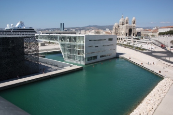 Sèten uutta vau-arkkitehtuuria. Musta museokuutio Mucem ja kongressikeskus. Taustalla renessanssiaan elevä Marseillen katedraali.